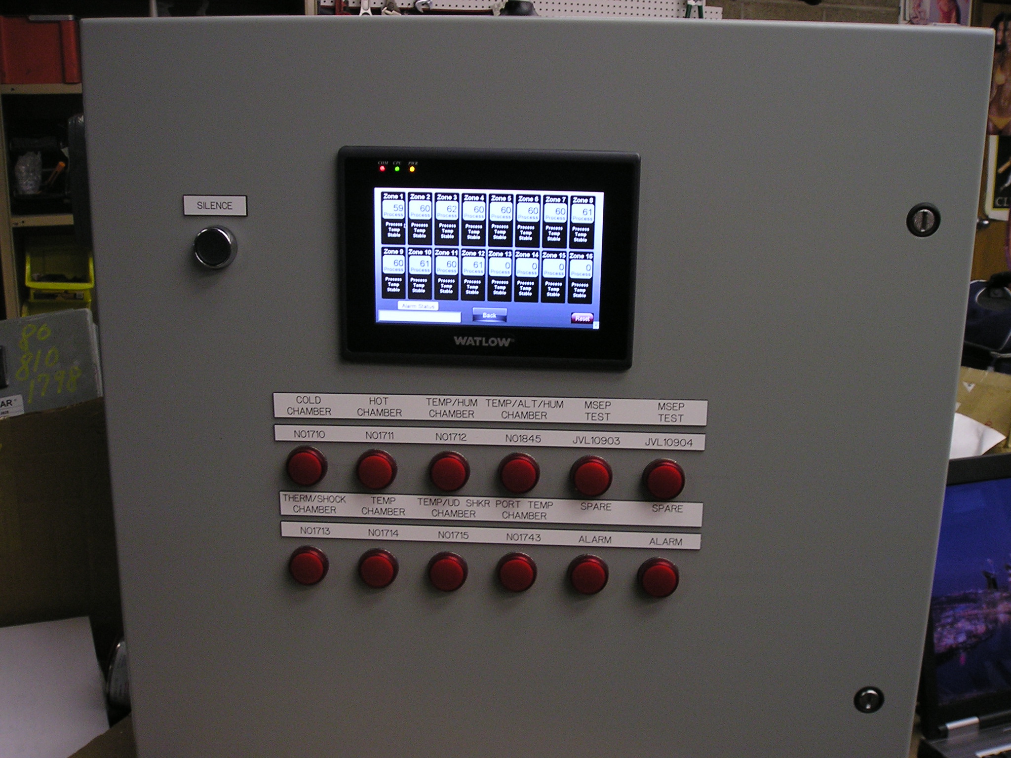 Touchscreen PLC and various alarm lights mounted on panel door.