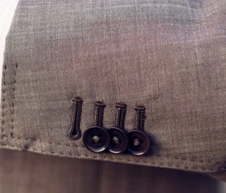 The surgeon cuff signals that the suit is bespoke. The one button undone is a subtle way of showing you have a custom made suit. If you want to take it back further, this style element gets its name from days when there were more physicians on the now iconic Savile Row than tailors. Once the suit makers moved in, they catered to their clientele by designing jacket and making jackets with functional sleeve buttons that could be unfastened and rolled back like shirt sleeves. This feature gave the Doctor the ability to work on a patient without removing his jacket, which is in stark contrast to the purely decorative and non-functional buttons that are attached to most suit jacket or blazer sleeves