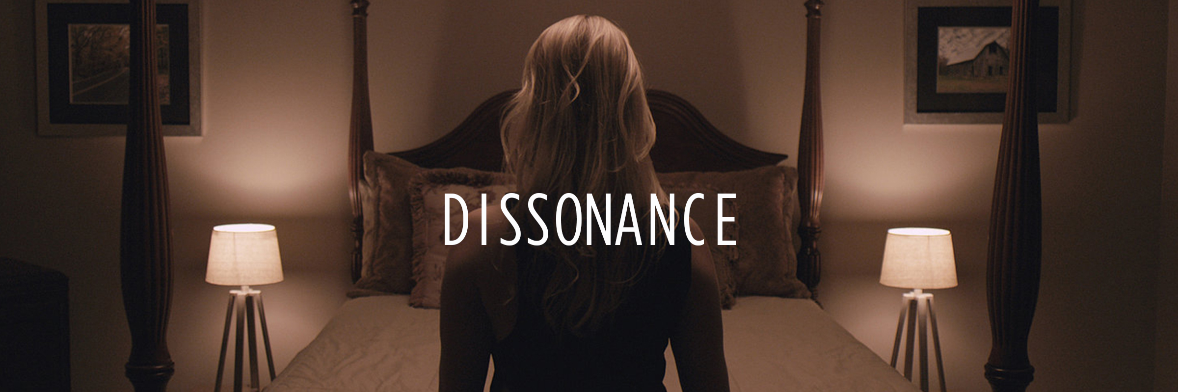 A woman with long, wavy blonde hair sitting on a bed with her back to the camera in a dimly lit bedroom. The bed has a dark wooden headboard and pillows. Two bedside lamps are on, casting warm light, and framed pictures are hung on the wall. The word 'DISSONANCE' is overlaid in the center of the image.