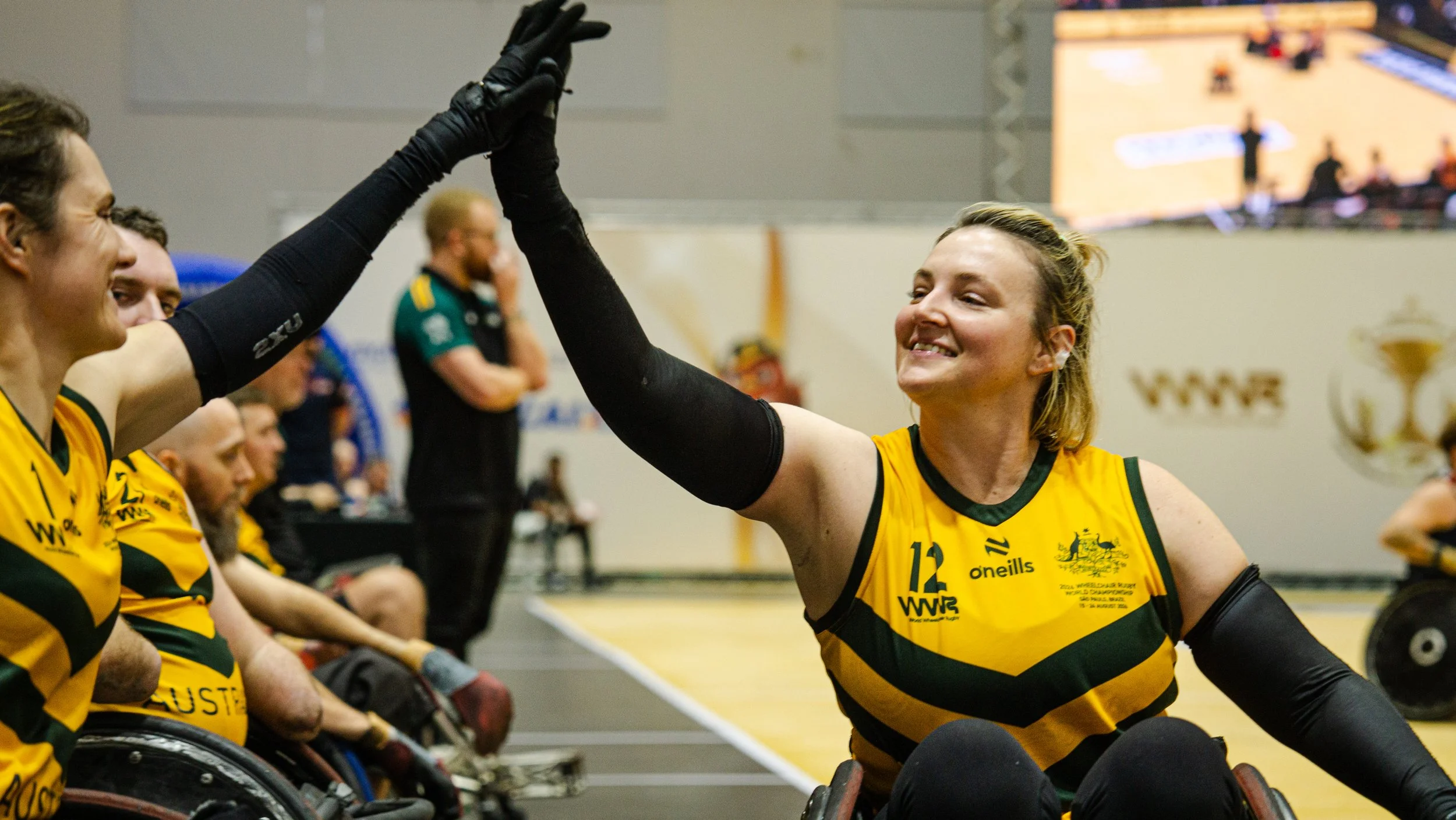 Athletes Ella Sabljak and Shae Graham celebrating together by high fiving courtside.