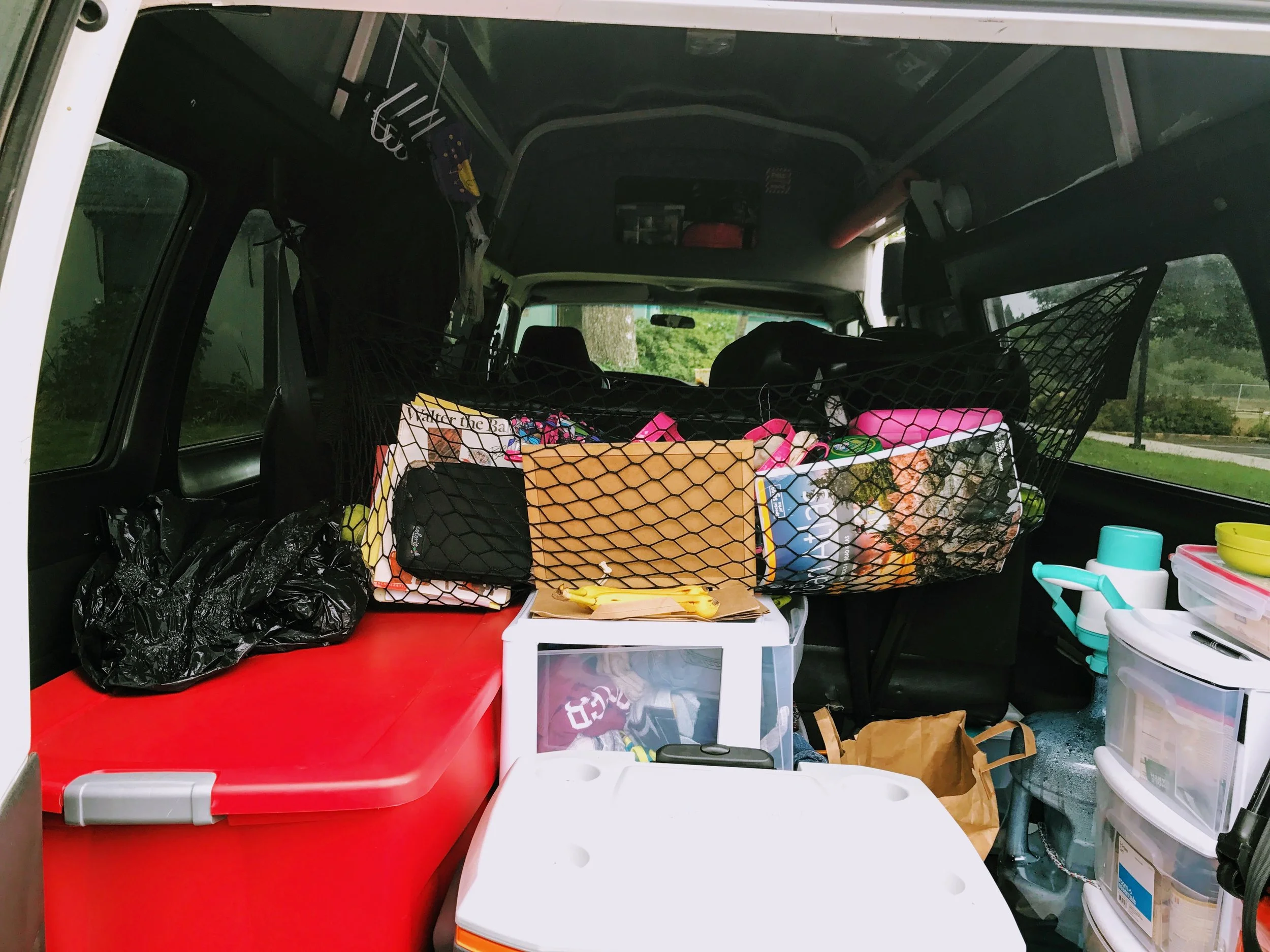 The back of the van: The Coleman "Fridge" the misc net, the food pantry, clothing behind the fridge, the dirty laundry bag, and the infamous red tote. This part of the van gets messy so quickly.