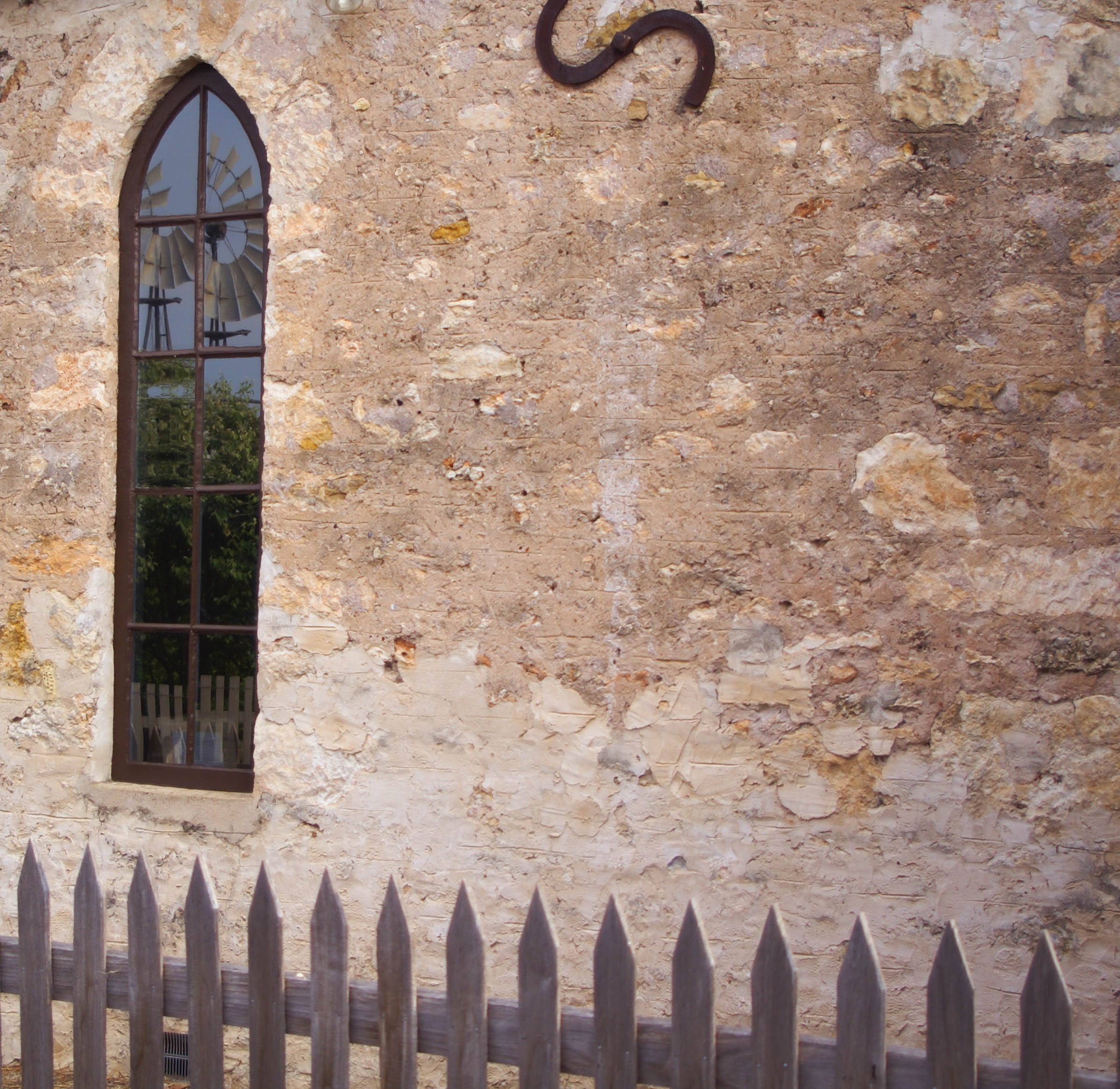 This has been taken along the side from Petticoat Lane and the windmill is reflected in the arched window. These were designed to allow maximum light into the school room. I love the honesty of the limestone wall. 