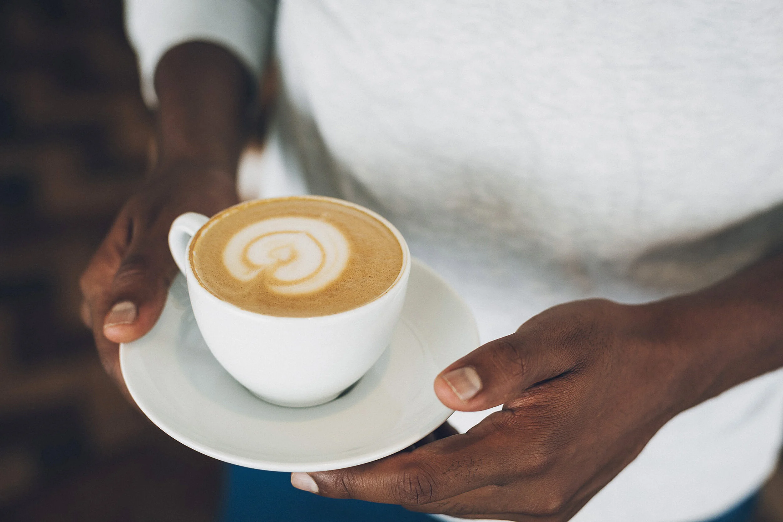 Hands holding cappuccino with latte art