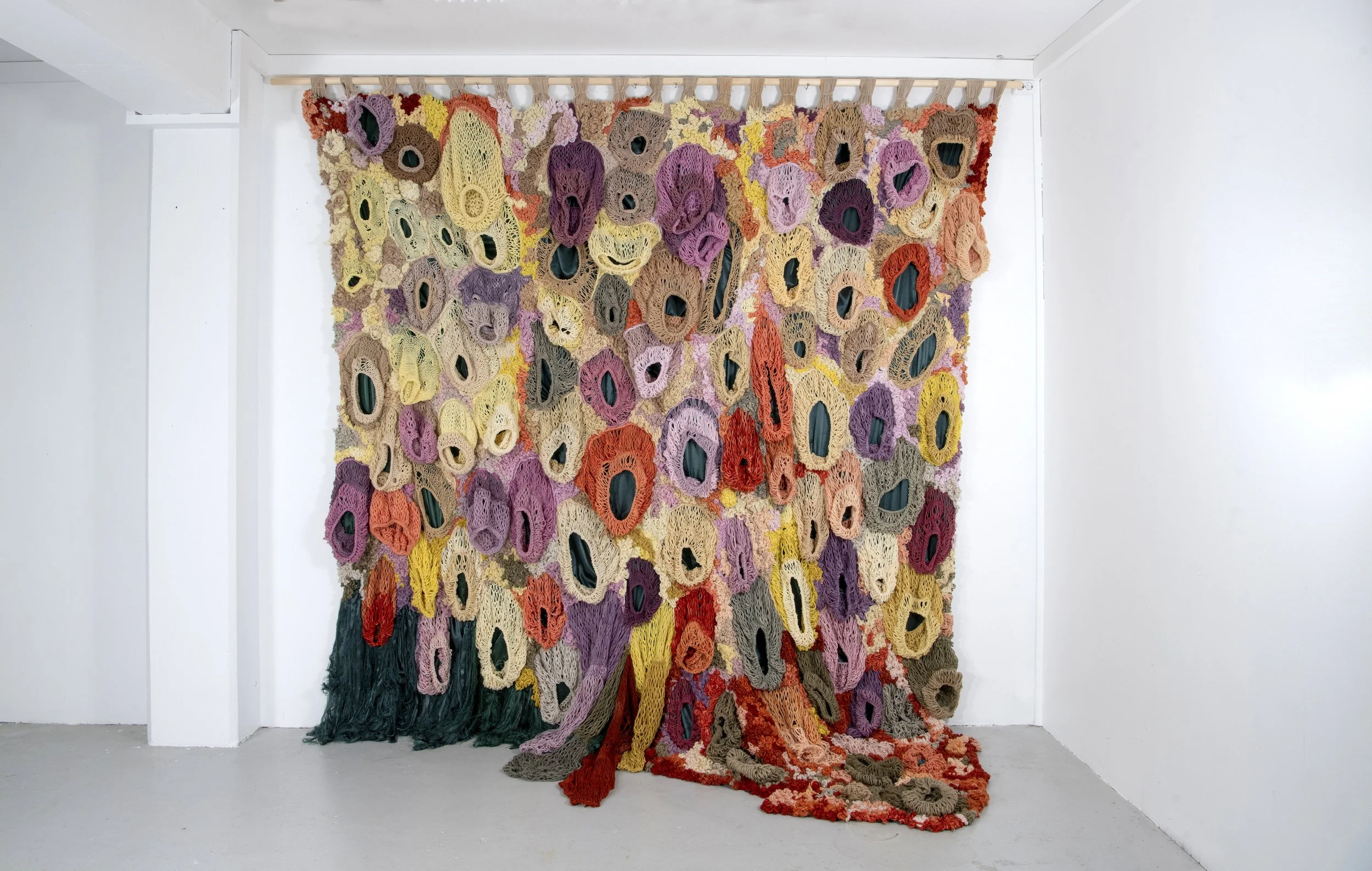 Ikke her. Ikke borte. (Not here. Not gone.) (2022)   Embroidery and knit on satin. Natural dyed yarn (pine cones, pine tree, avocado, cochenial insect, spinach, birch, madder, rhubarb, tree lichens). Wood.  4,04x3,28m