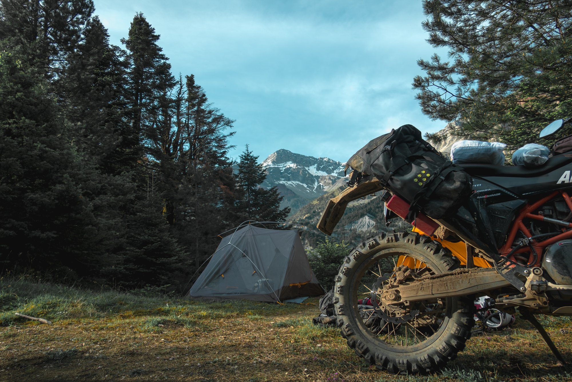 Motocicletă de călătorie cu bagaje lângă cort într-o imagine oficială KRIEGA