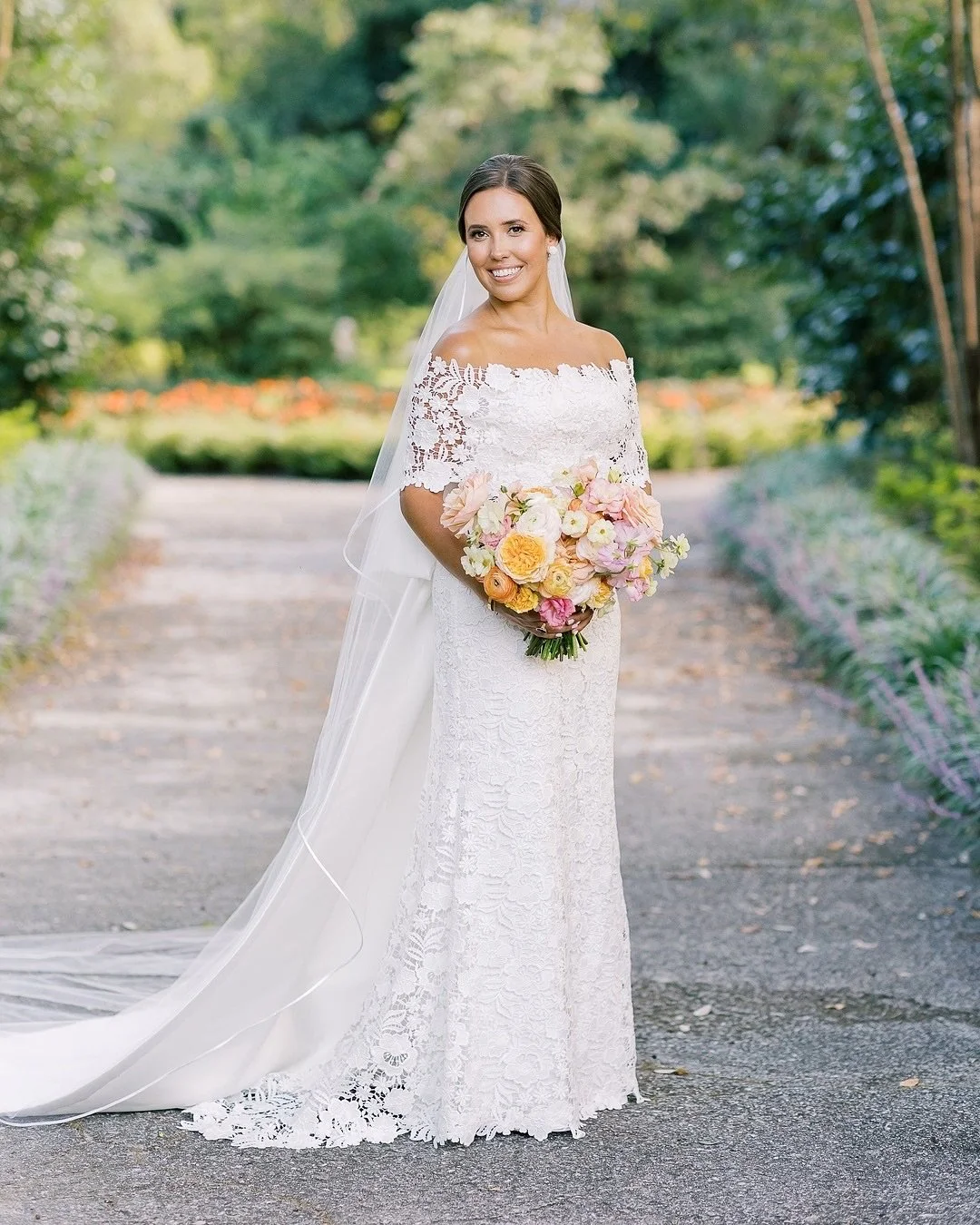 Romance in full bloom 🌿 Sophia was a vision of timeless grace in her floral lace Lela Rose gown as she and Tyler exchanged vows beneath the Live Oaks. From the delicate off-the-shoulder wrap to the dramatic satin bow, every detail reflected the effo