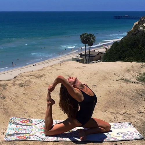 A bright, festive Vagabond Goods mat is the perfect beach-side yoga accessory. Bodysuit by Shakti Wear.