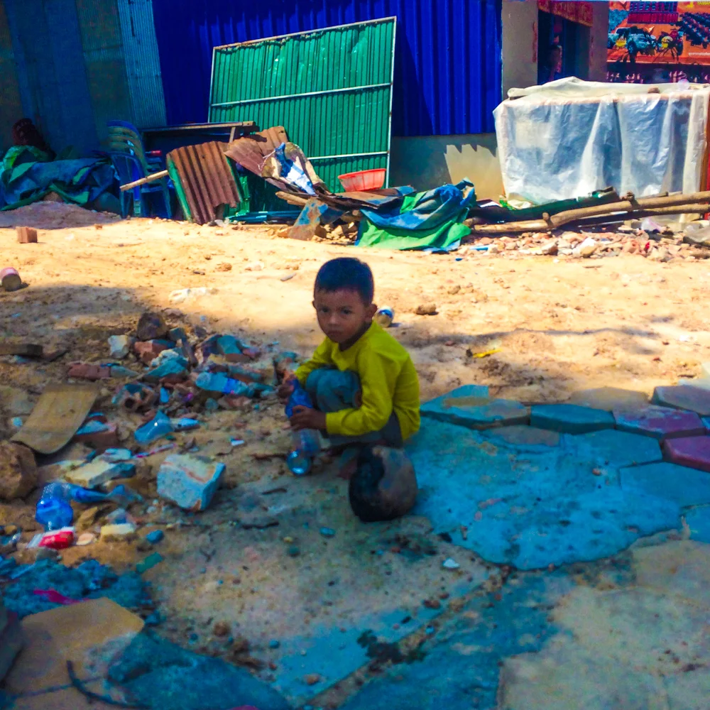 A child plays with trash on the side of the road in Sihanoukville, Cambodia.