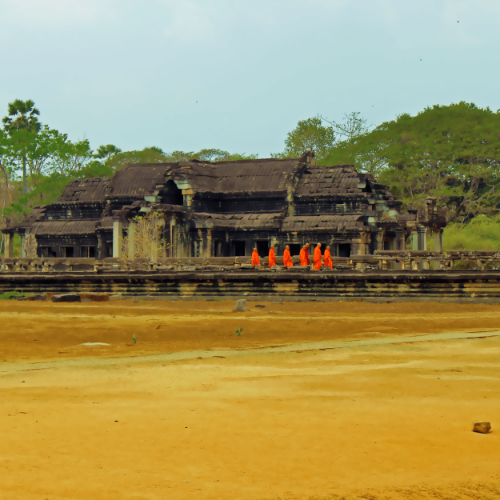 A group of monks walking towards one of the temples of Angkor Wat.