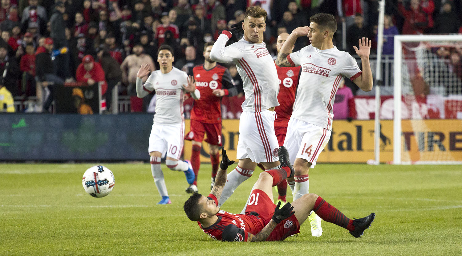 Sebastian Giovinco laying on the ground as two Atlanta United FC players act as if nothing had happened. Image by Dennis Marciniak.