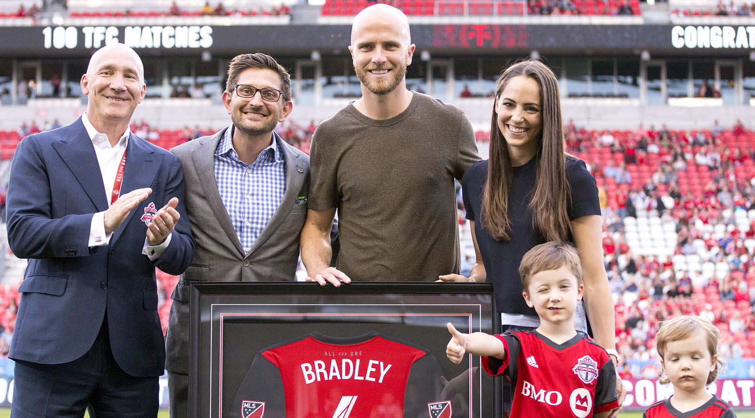 Bill Manning , Tim Bezbatchenko, Michael Bradley, and his wife Amanda Barletta pose with a commemorative jersey for Michael Bradley's 100th match with Toronto FC. Image by Dennis Marciniak of denMAR Media.