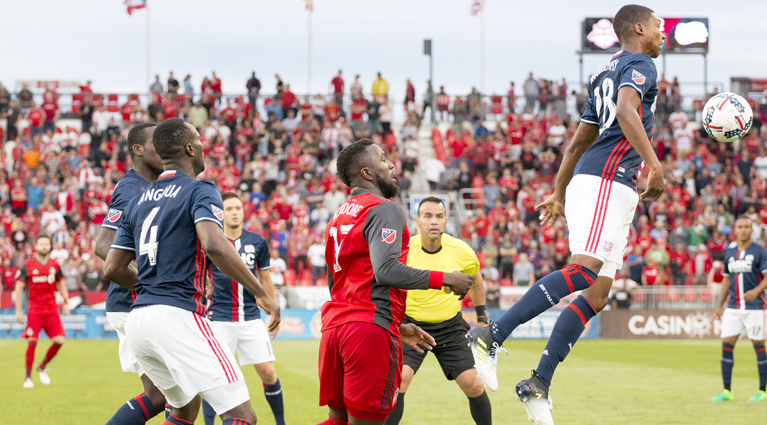 A New England Revolution defender pushes the ball with his chest away from Jozy Alitdore during an Major League Soccer match in 2017. Image by Dennis Marciniak of denMAR Media.