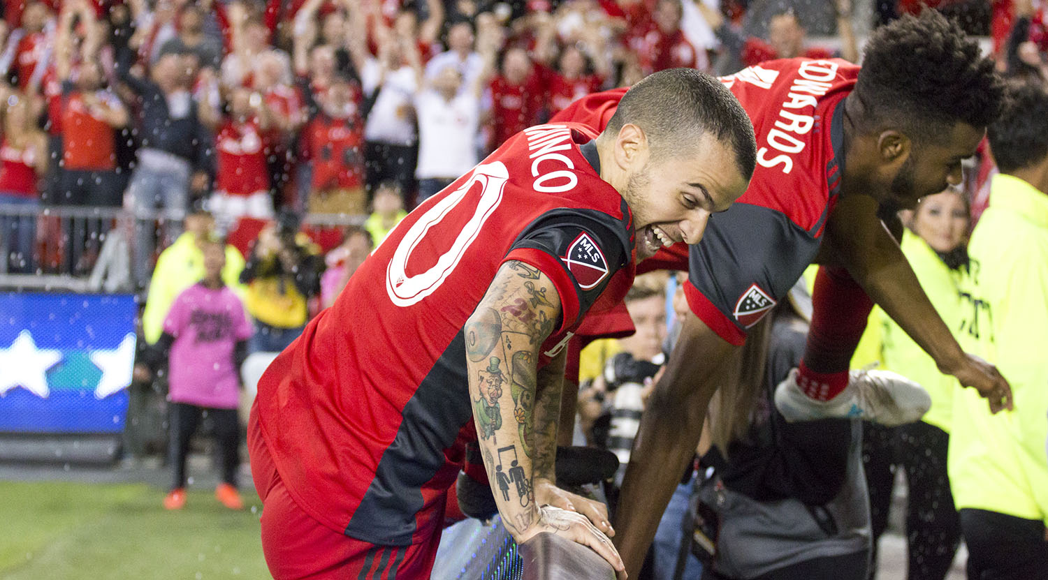 Raheem Edwards and Sebastian Giovinco jump the boards to celebrate with fans after scoring a second goal to win the match late into injury time to take the Canadian Championship! Image by Dennis Marciniak of denMAR Media.