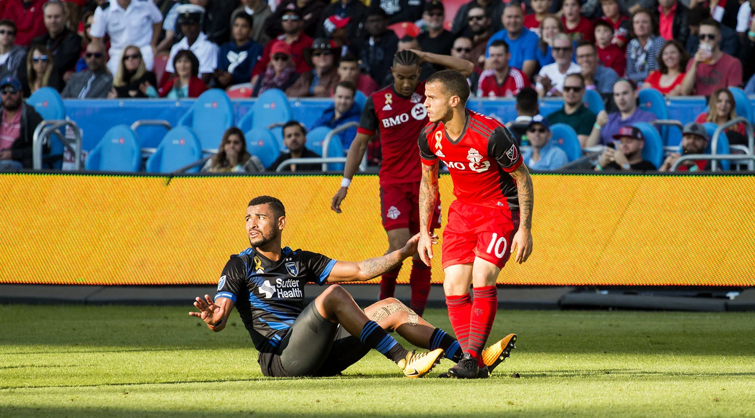 Sebastian Giovinco and a San Jose Earthquakes player clash in a shaft of light during a regular season MLS match. Image by Dennis Marciniak of denMAR Media.