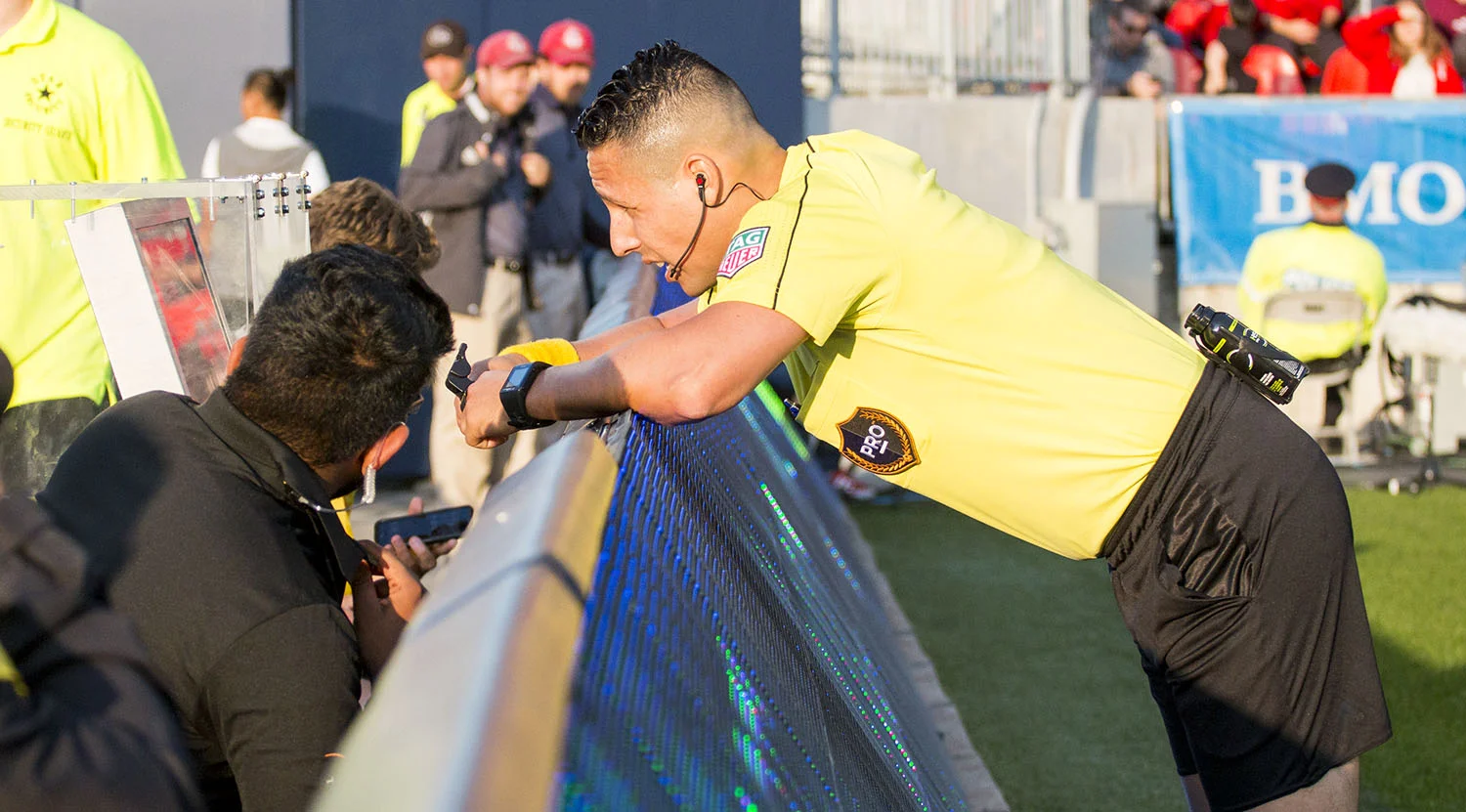 Referee Jose Carlos Rivero check the call by Video Assistant Referee Yusri Rudolf that would result in a red card during the first Video Review at BMO Field. Image by Dennis Marciniak of denMAR Media.