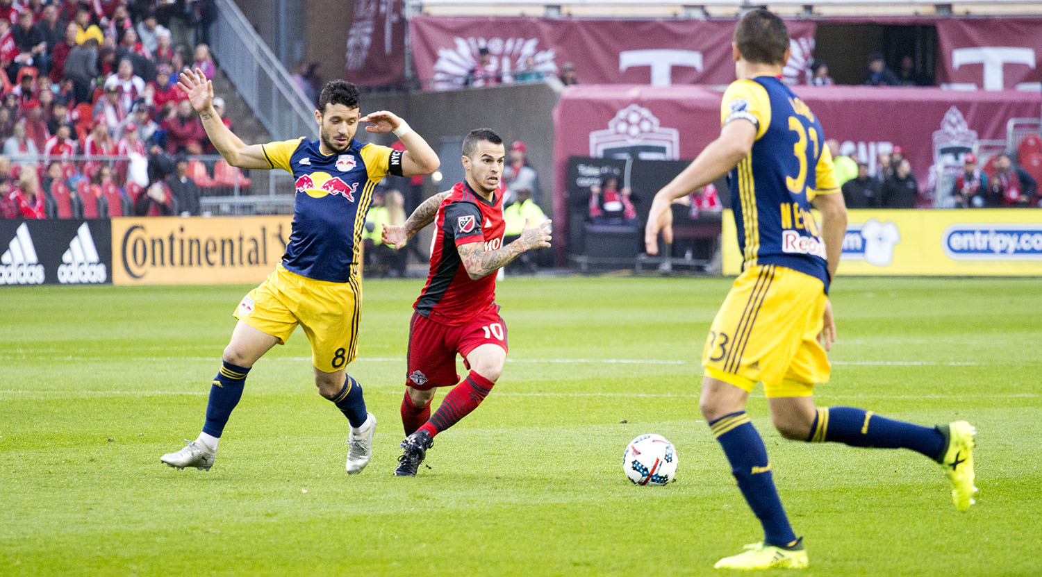 Sebastian Giovinco tries to get the ball past two NYRB defenders during a 2017 MLS playoff game. Image by Dennis Marciniak of denMAR Media.