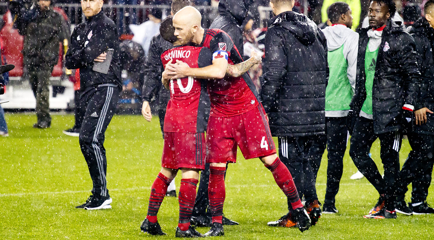 Sebastian Giovino and Michael Bradley give each other a hug in the rain after advancing 2-2 on away goals to the next round of the MLS playoffs.