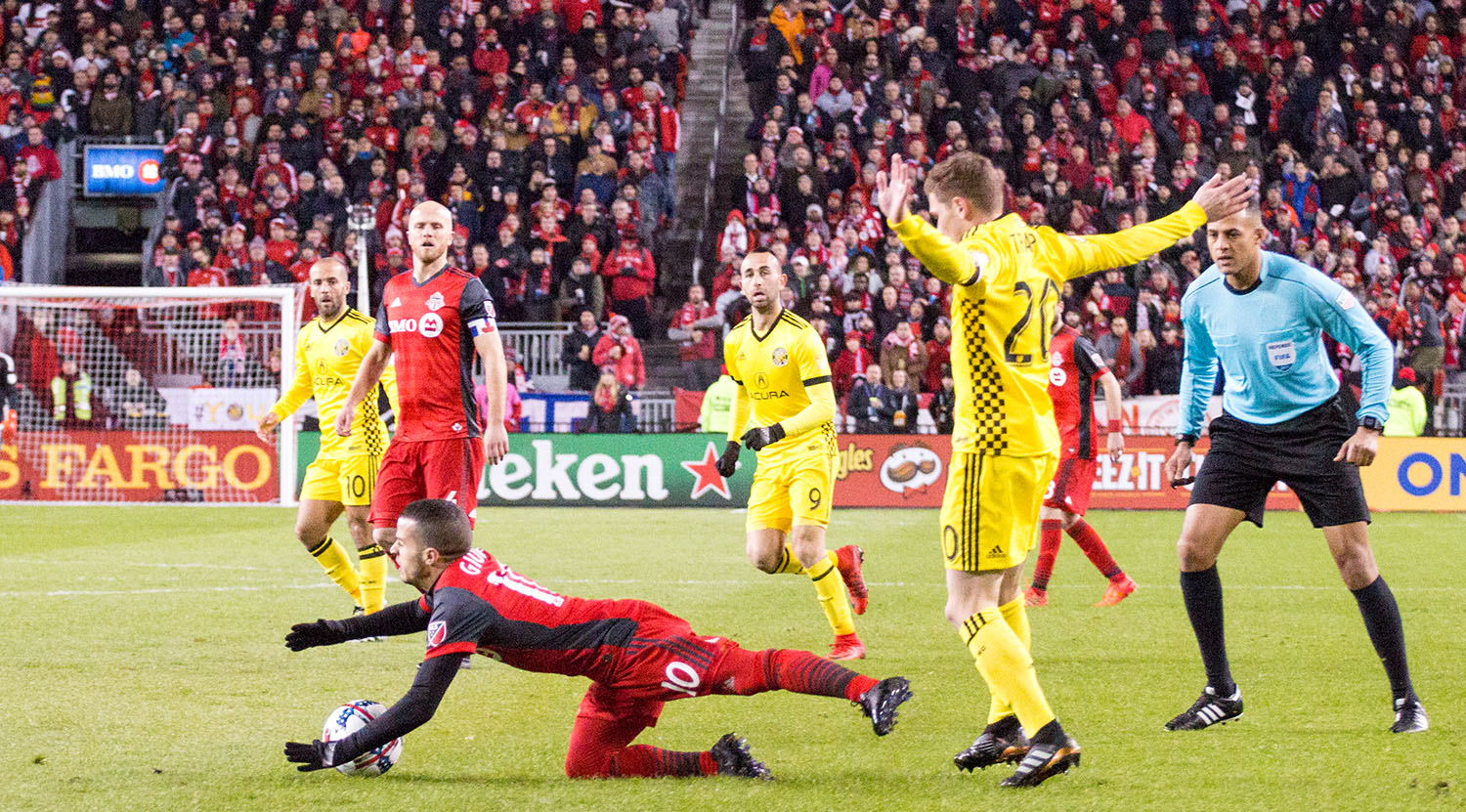Sebastian Giovinco is taken down to ground as Ismail Elfath looks on. Image by Dennis Marciniak of denMAR Media.