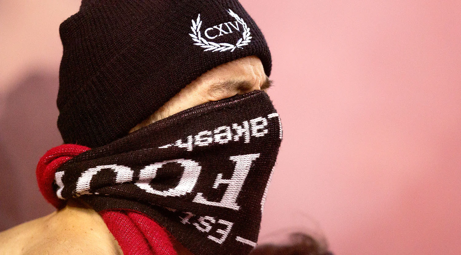A Toronto FC South End Supporter covers his face as smoke fills the stadium during the 2017 Major League Playoffs. Image by Dennis Marciniak of denMAR Media.