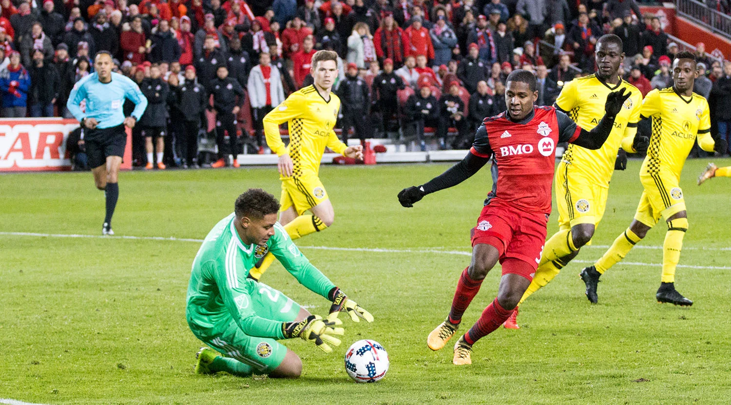 Armando Cooper trying to get to the ball before the Columbus Crew goalkeeper can get to it. Image by Dennis Marciniak of denMAR Media.