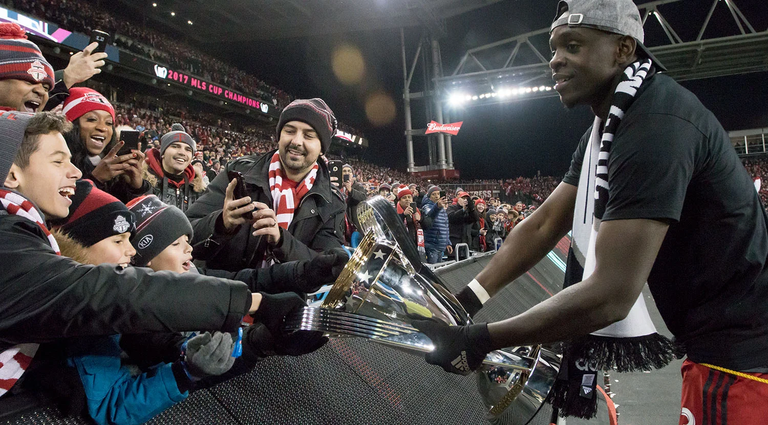Chris Mavinga lets some young supporters touch the MLS cup as he brings the trophy the east end. Image by Dennis Marciniak of denMAR Media.