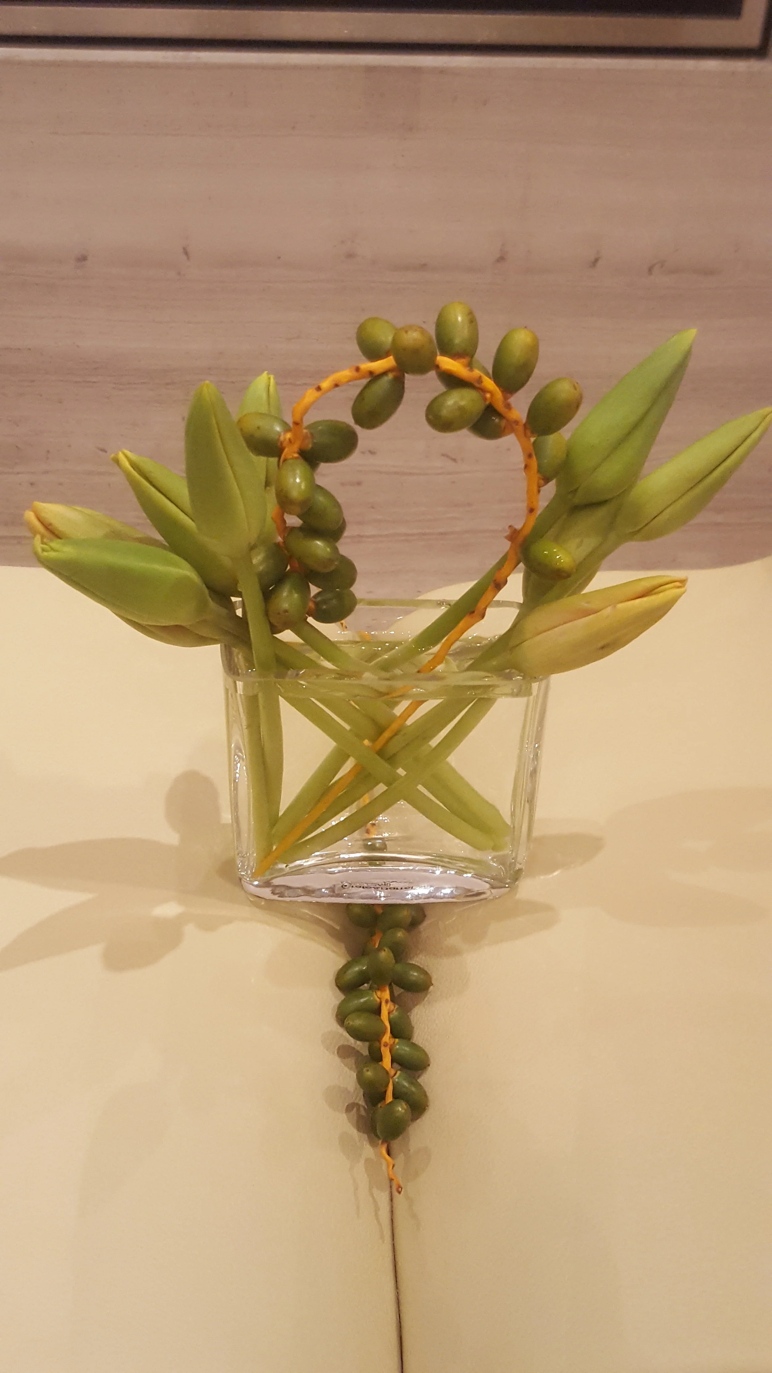 Tall brown vase with holes at the top and white lizanthus tucked into it on the side