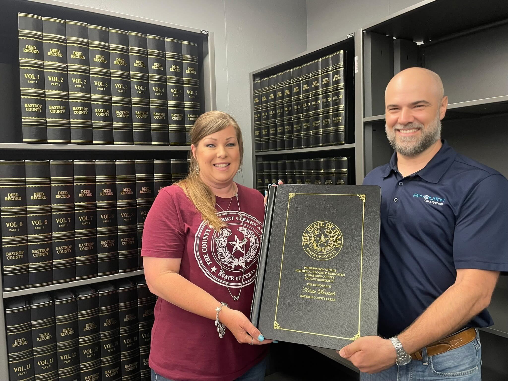 Two people holding up a book of the state of texas