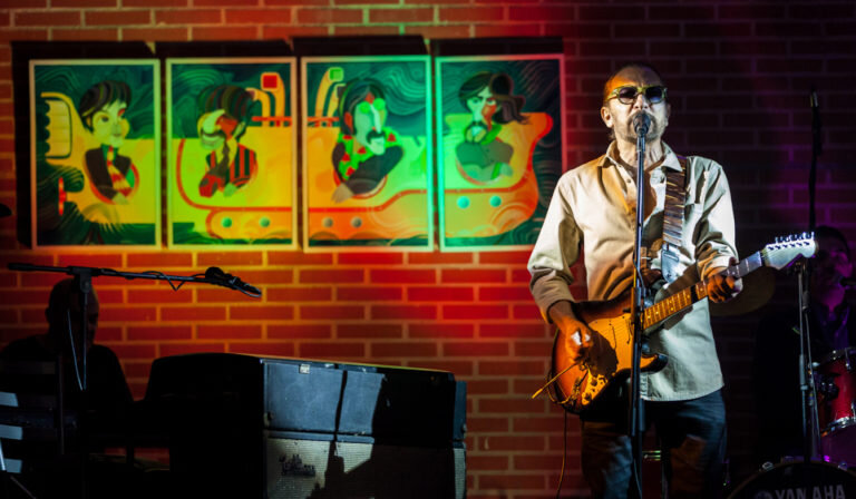 Jorge Spiteri en concierto en Caracas en 2013. El escenario, decorado con obras de Edo Sanabria sobre los Beatles | Fotografía de Daniel Guarache Ocque