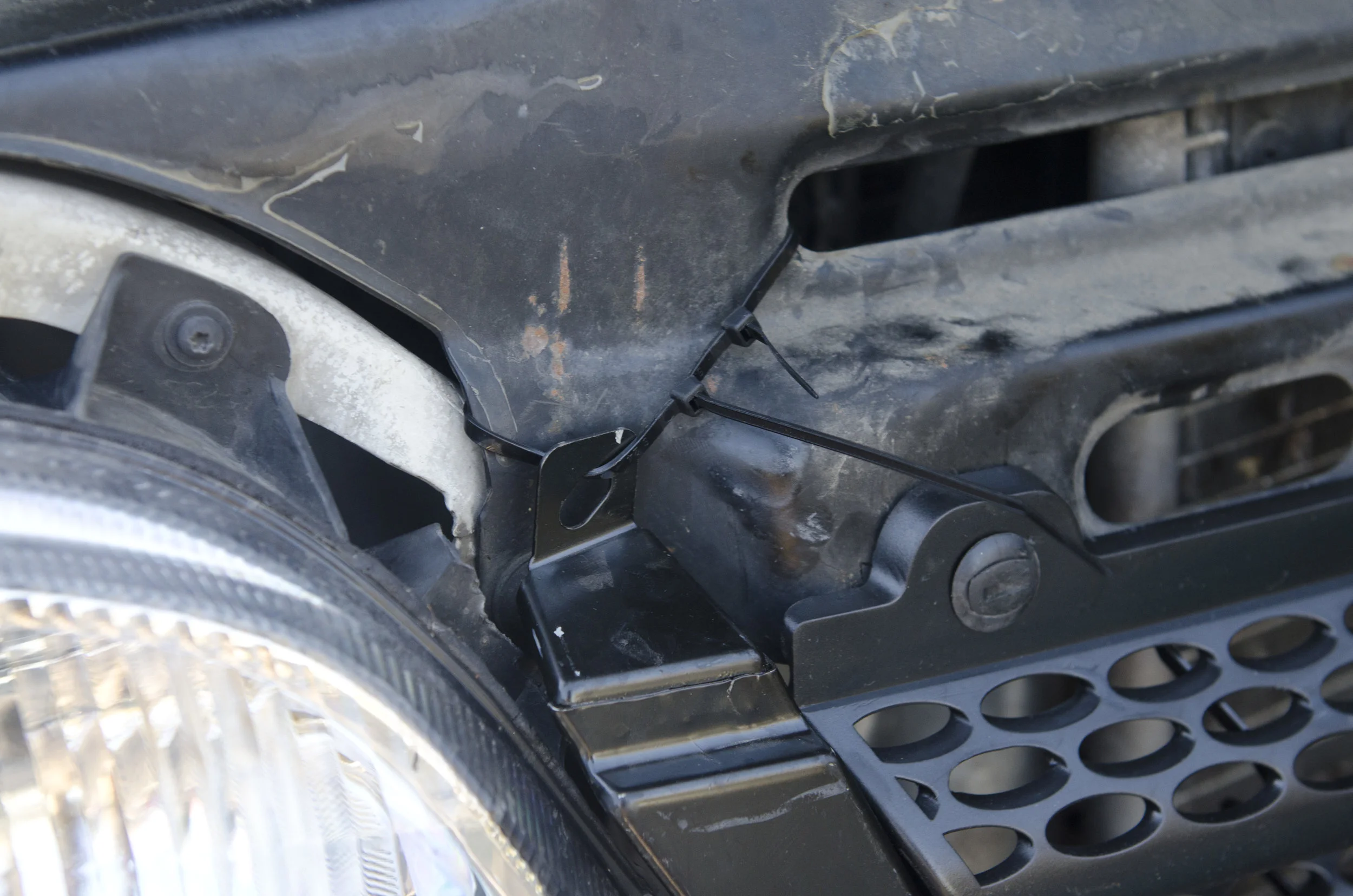 Zip tie through extra attachment point on the left side of the grille