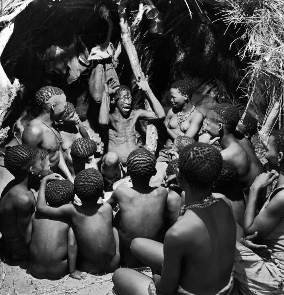 legrandcirque:
Bushman children sitting around their chief as he acts out a story. Photograph by Nat Farbman. Southern Kalahari Desert, Botswana, 1947.