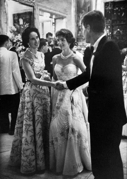 everything-kennedy:
Sen. John Kennedy shaking hands w. socialite Mrs. John Drexel III as his wife Jacqueline, pregnant w. daughter Caroline, clad in beaded & shirred white evening gown featuring a big full skirt, looks on adoringly, during bene…