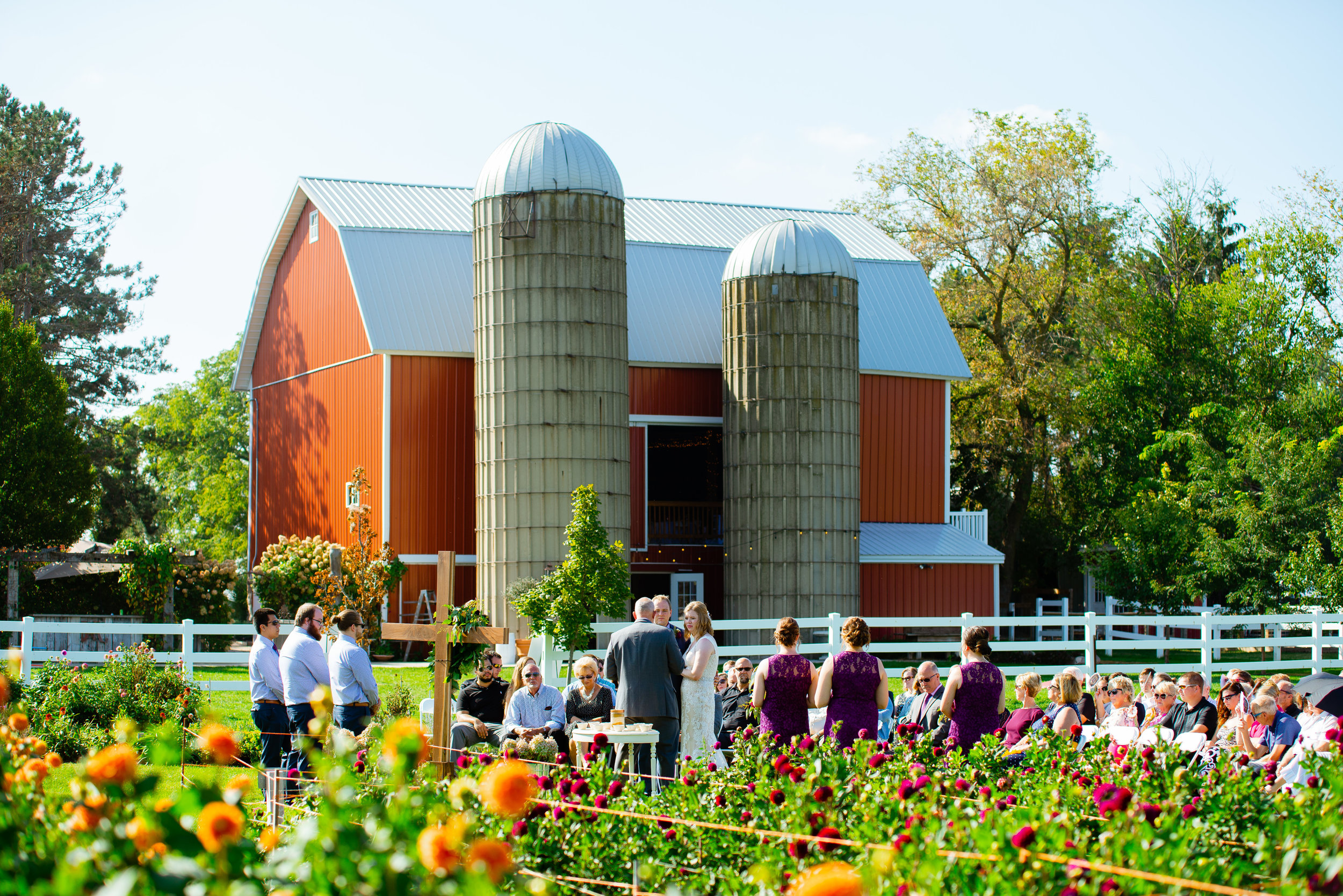 Wedding ceremony in flower garden behind barn