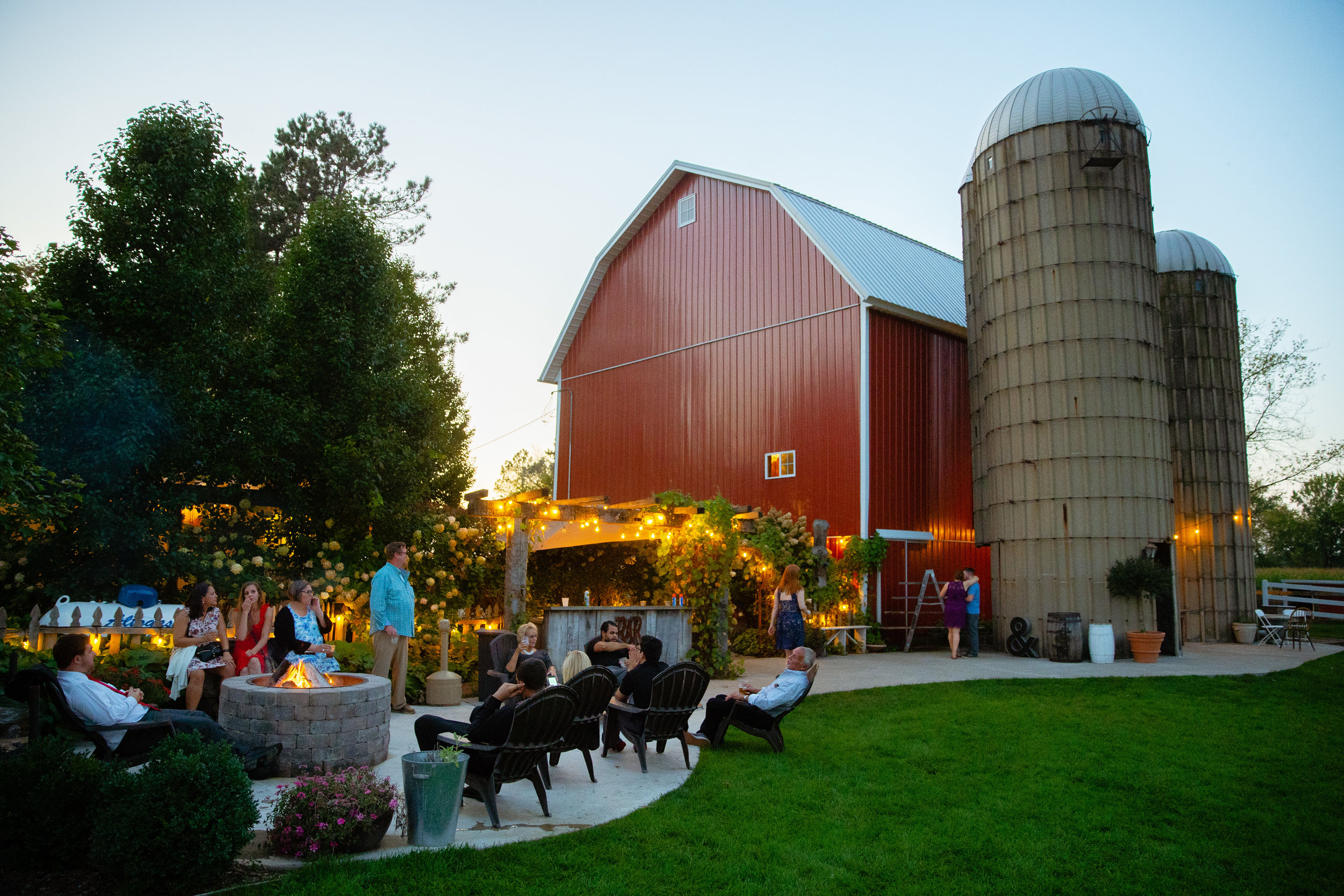 barn courtyard at dusk with bonfire pit and bar