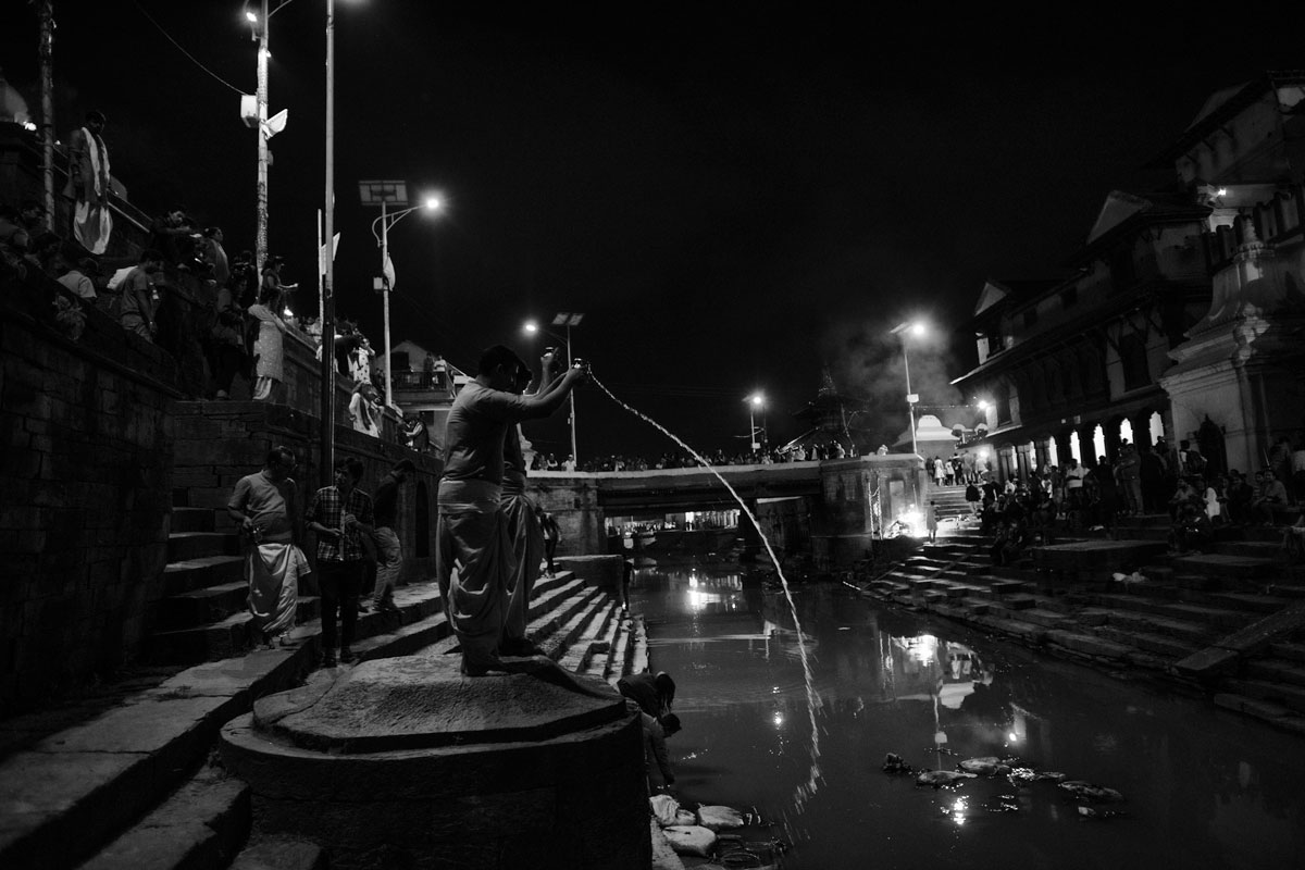 A devotee offers water to the river Bagmati. After the every day Aarti at Pashupatinat. Aarti is a Hindu religious ritual of worship.