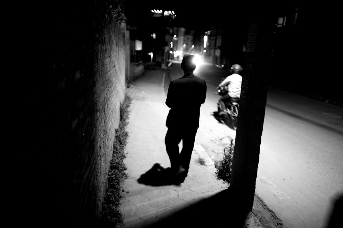 A man is walking under a streetlamp in Boudha, Kathmandu, Nepal.