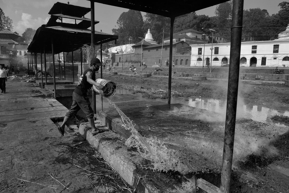 Antyeṣṭi, "last sacrifice" Pashupatinat, on the banks of the Bagmati River. An assistant rinses the Shmashana from the last remains after a cremation. A shmashāna is a Hindu cremation ground, where dead bodies are burnt on a pyre.