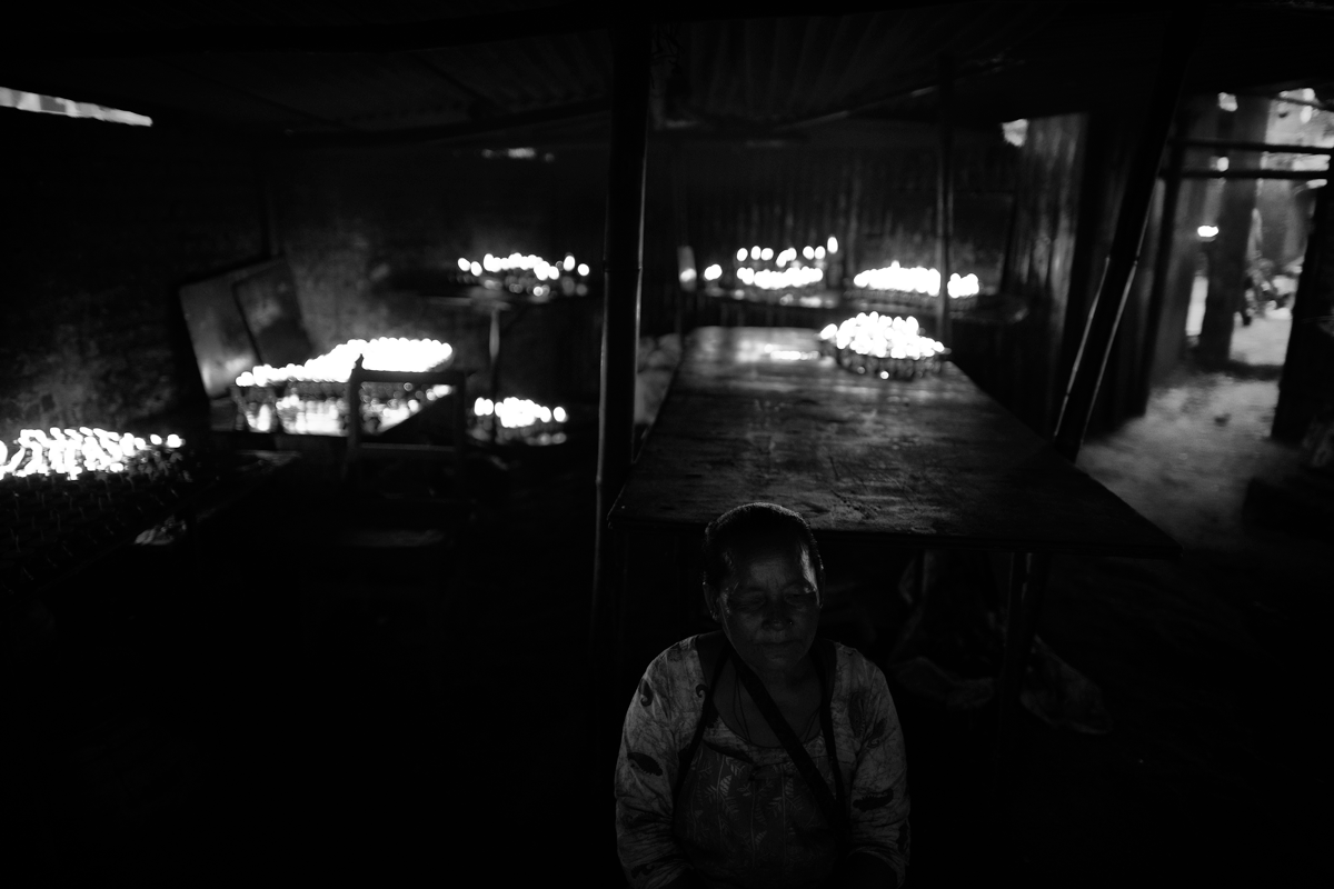 Buddhist devotee offerrs buttercandels to light near Boudhanath Stupa. Butter lamps are offered during meditation practice or ceremonies with the wish that all beings be free of suffering and reach enlightenment.