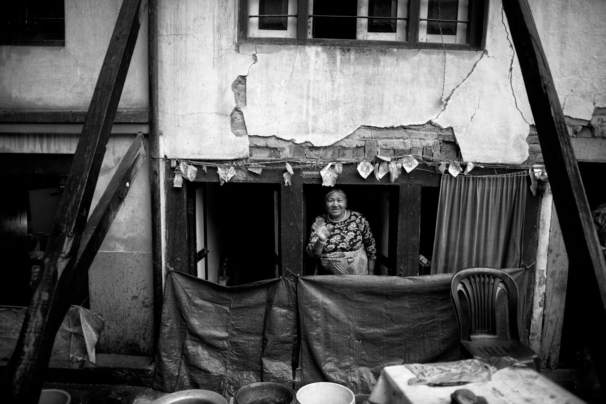 A woman waves to me in her house, which has been severely damaged by the earthquake in 2015.