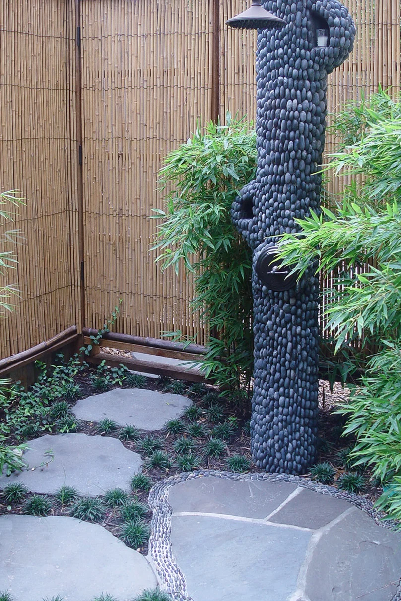 This outdoor shower is surrounded by natural-looking rock speakers.