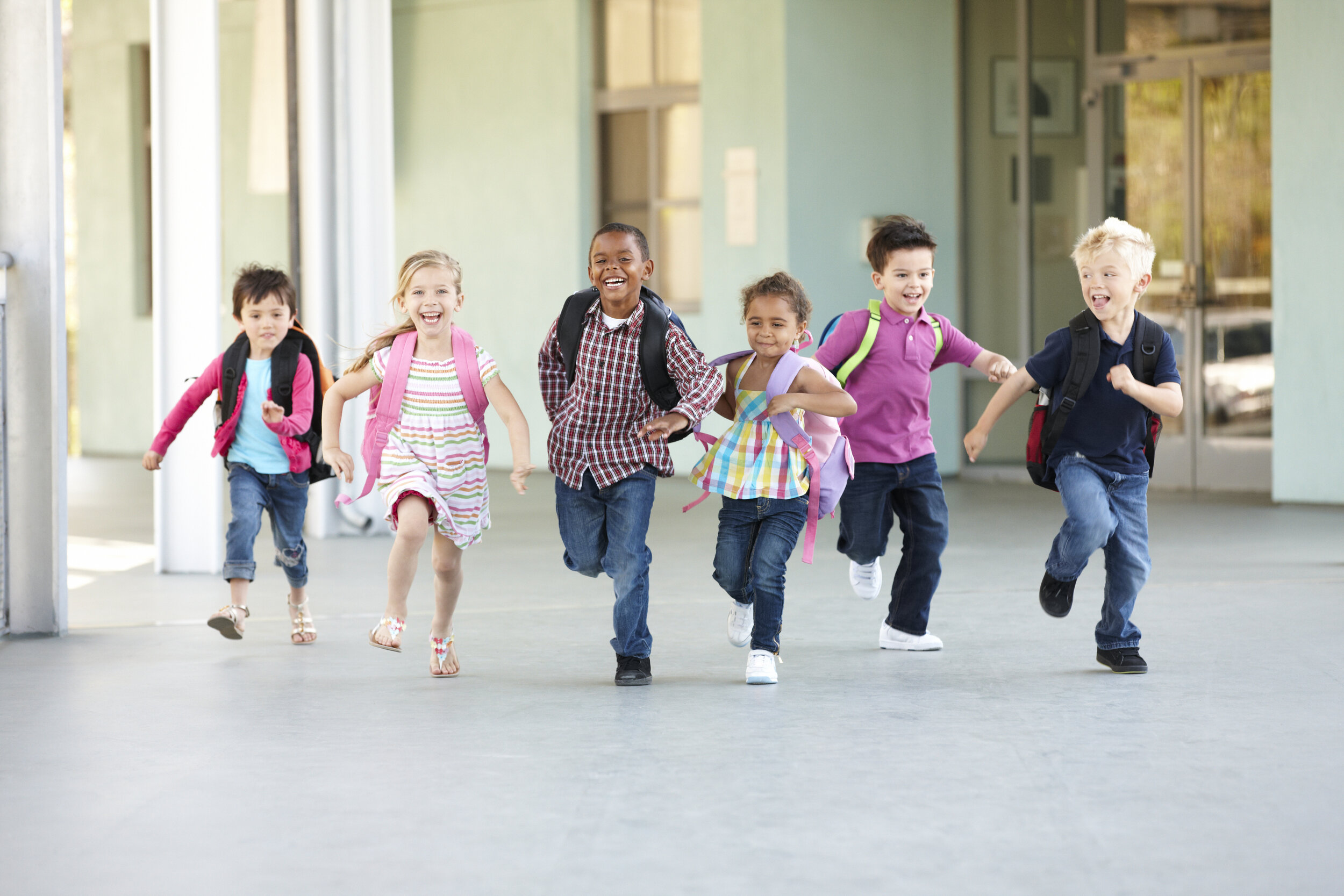 Young children wearing backpacks running