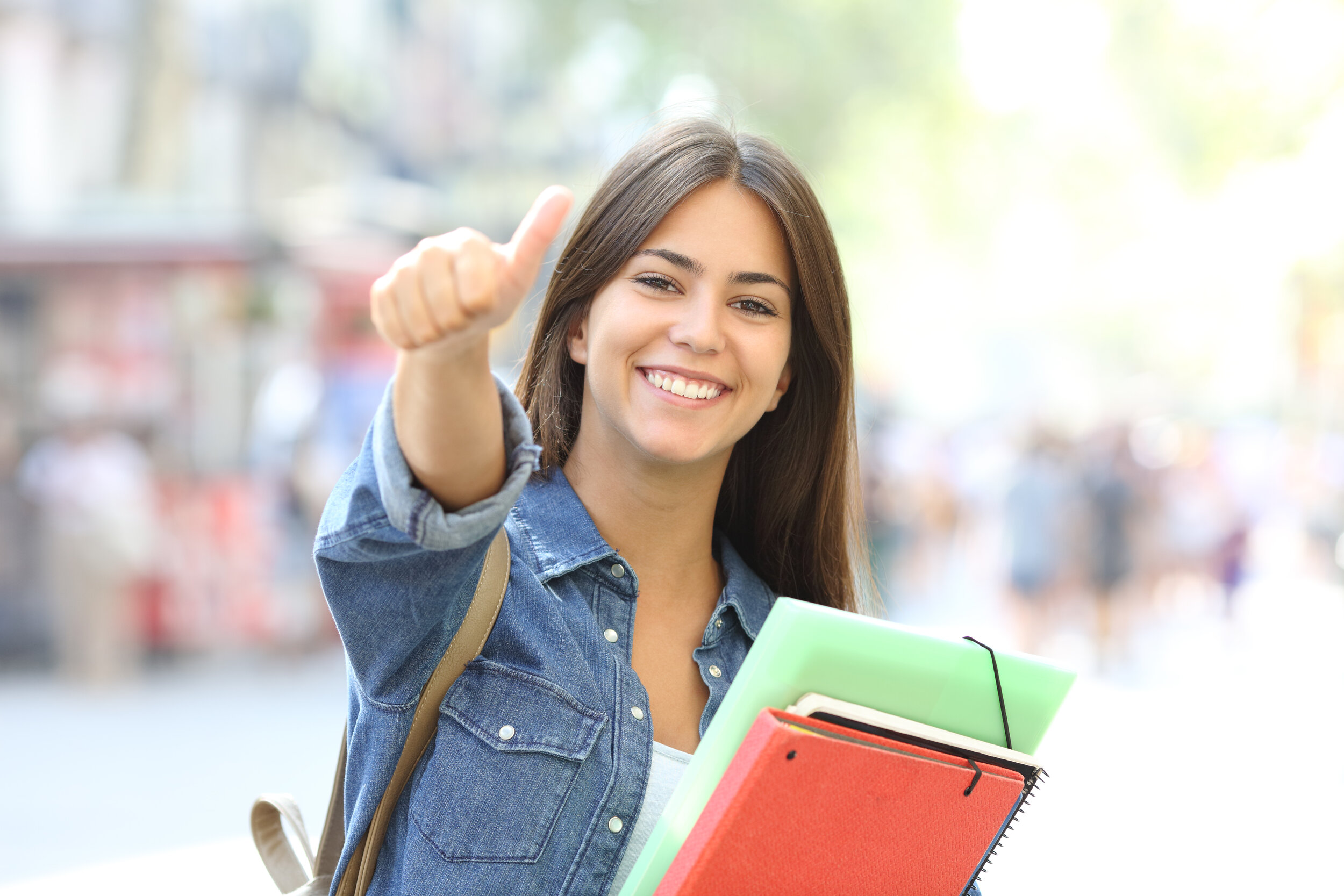 Teen holding schoolbooks and giving thumbs up sign