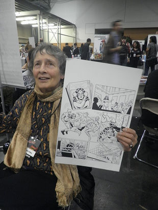 Ramona Fradon holding a page of her original art.