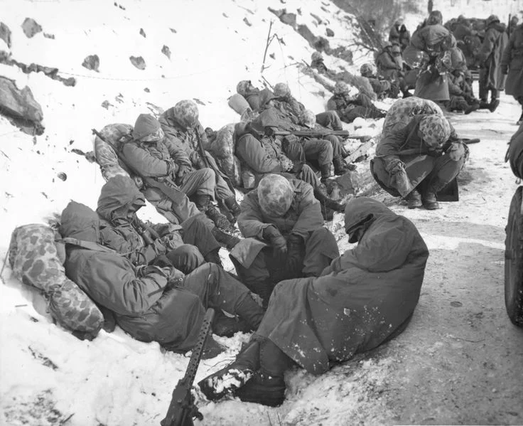 Leathernecks from the 7th Marine Regiment are able to catch a few moments rest during their heroic breakout from the Chosin Reservoir on December 6, 1950. 