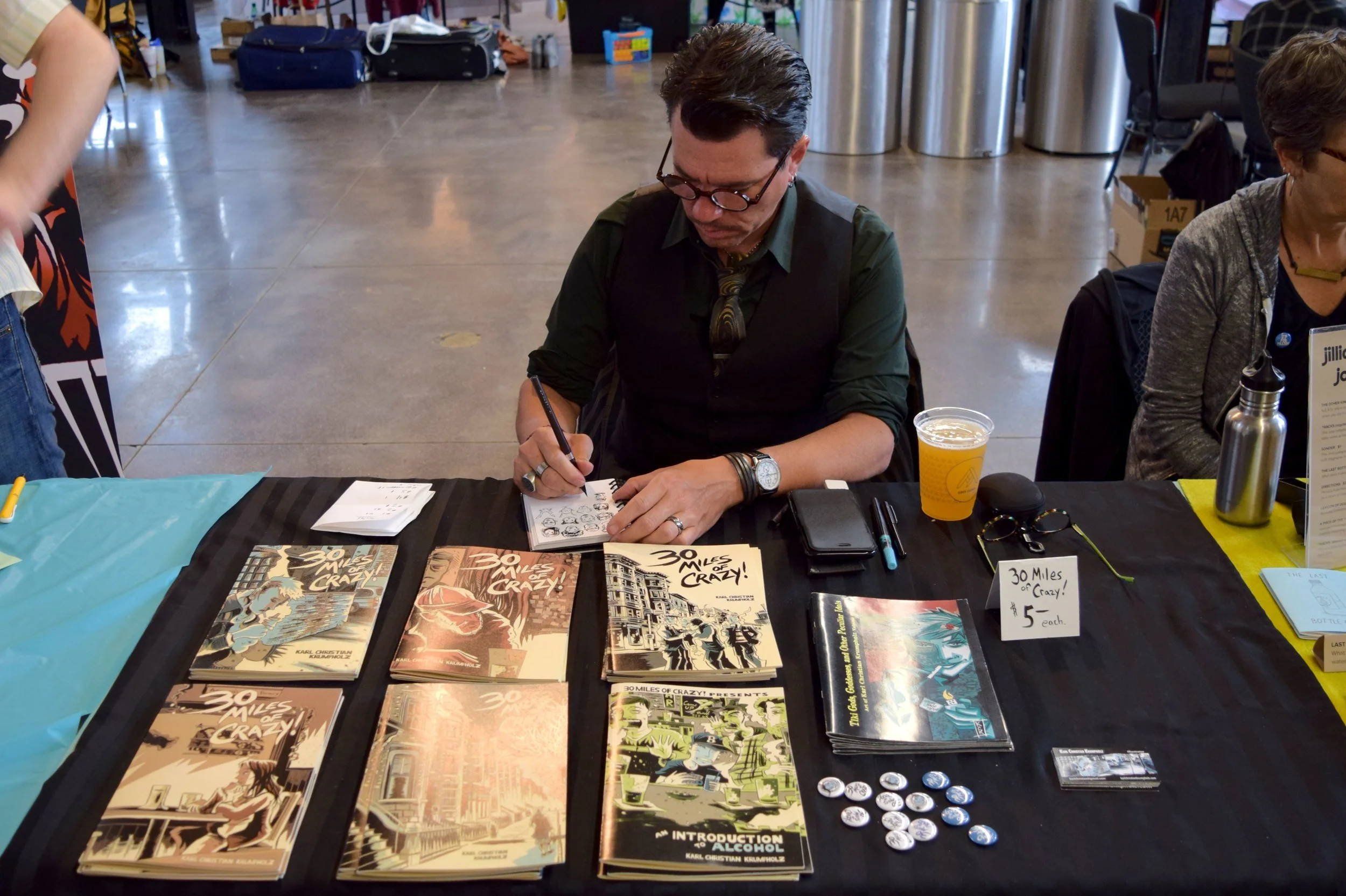Karl Christian Krumpholz drawing silly faces at Denver Zine Fest 2018 .
