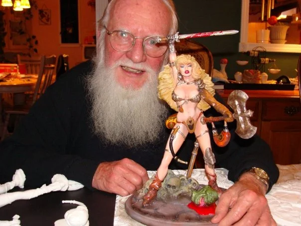 Frank Thorne posing with a Red Sonja statue.