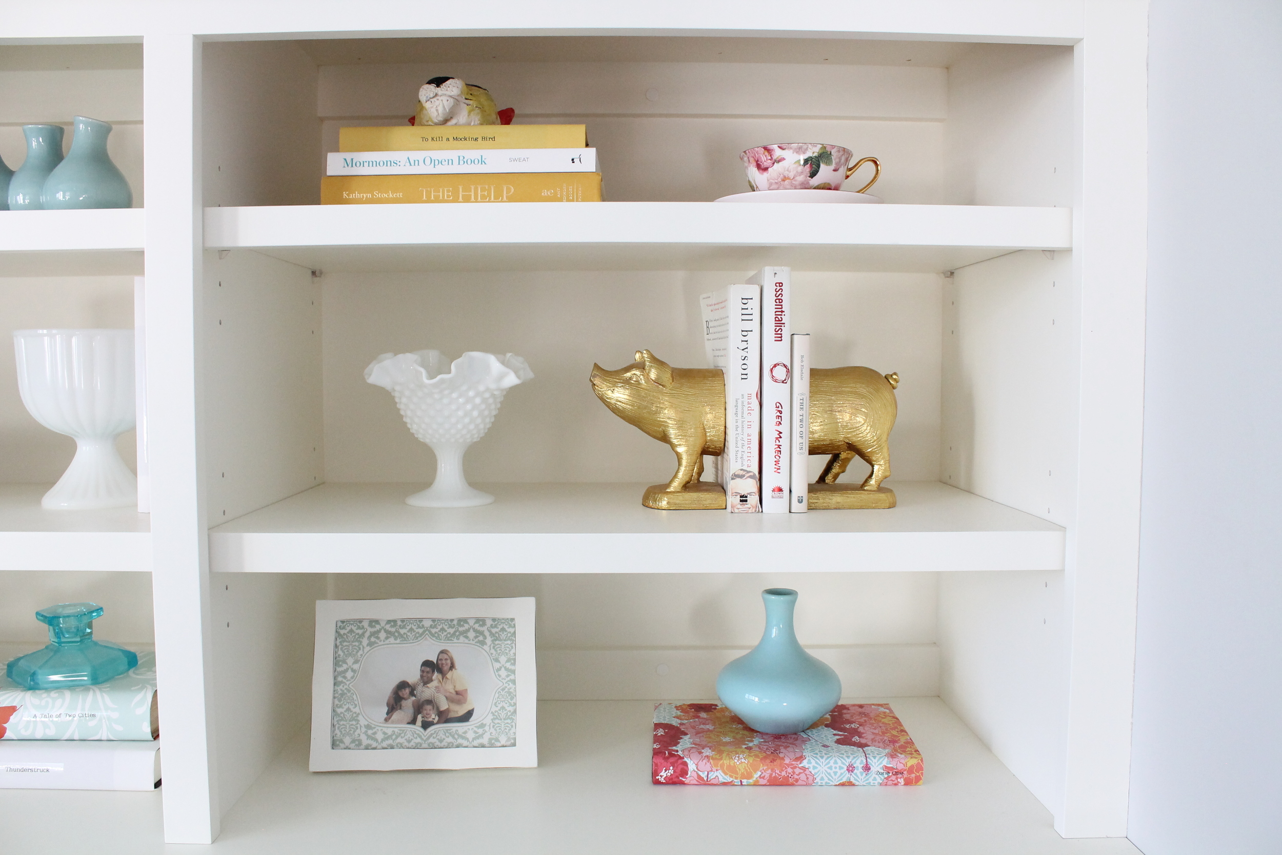 Built in bookshelf decorating ideas. Style a bookshelf with a cohesive color pallet by covering books with pretty paper. Add some glass objects and small frames to round out the design.