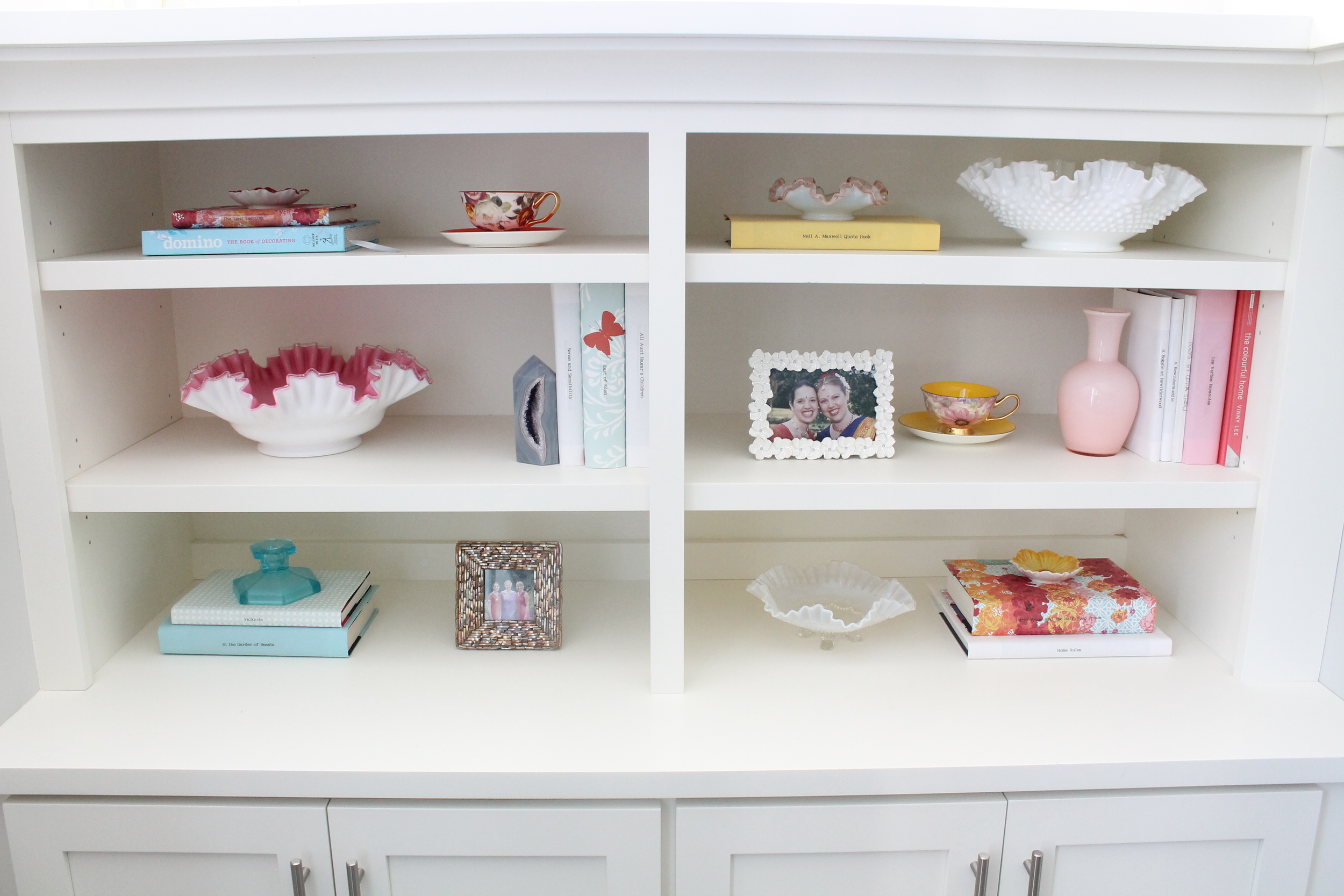 Built in Bookshelf styling with paper covered books and vintage ruffled glass bowls.
