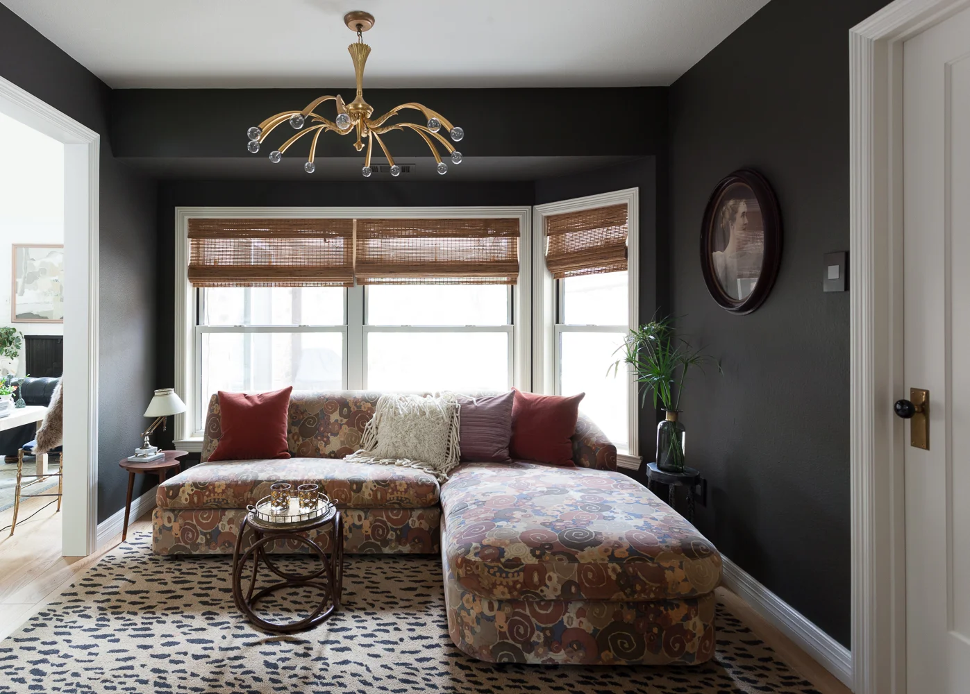 Dark and moody den with pattern on pattern sectional and Metrie door.