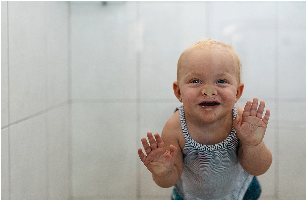 toddler pushing her face in a shower door