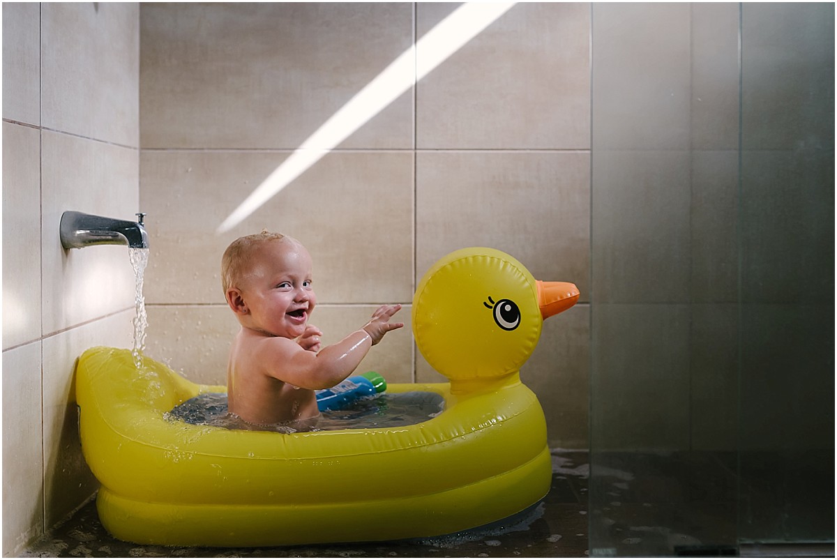 little girl taking a bath in a rubber ducky tub